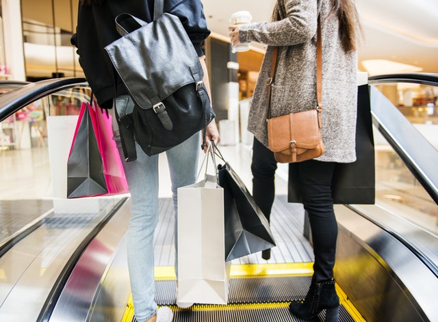 people holding shopping bags on a mall escalator 