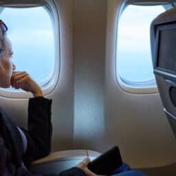 Side view of a woman traveling in plane and looking out of the window