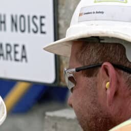 Man at construction site wears earplugs